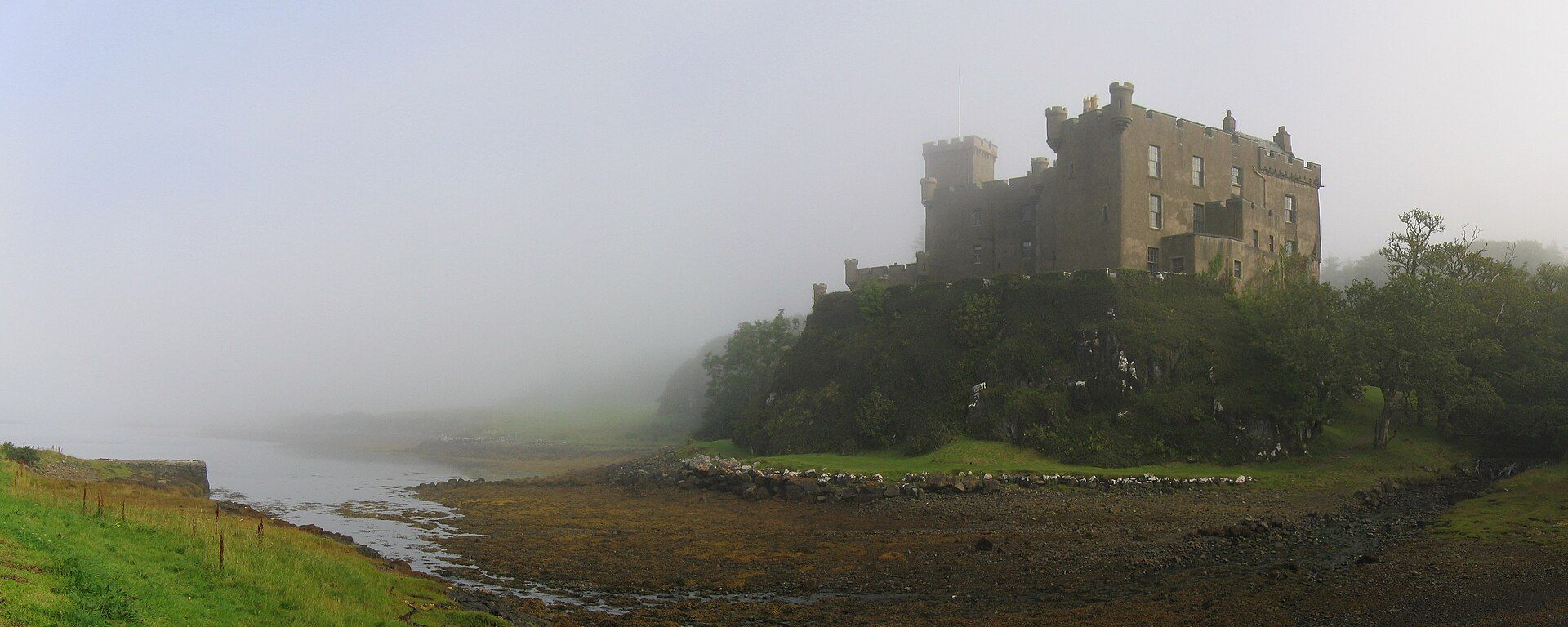 Dunvegan Castle rising from the shore in morning mist, Isle of Skye.